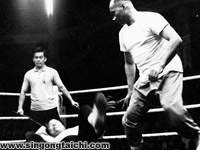 Huang (foreground) defending a challenge by a wrestler (on the ground). Yek Sing Ong (background) was the referee representing Huang.